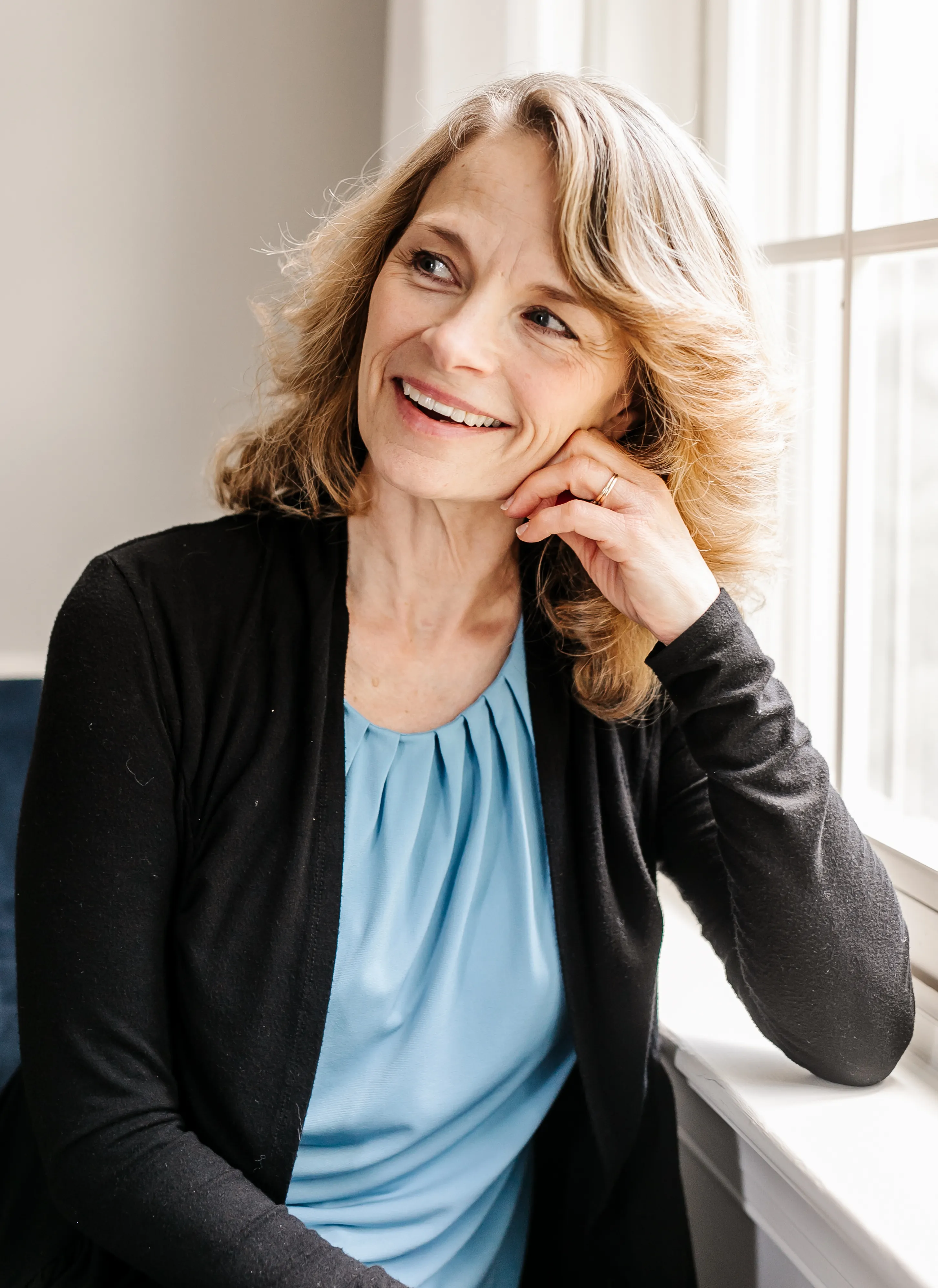 A woman in her fifties with a warm, relaxed expression in soft daylight
