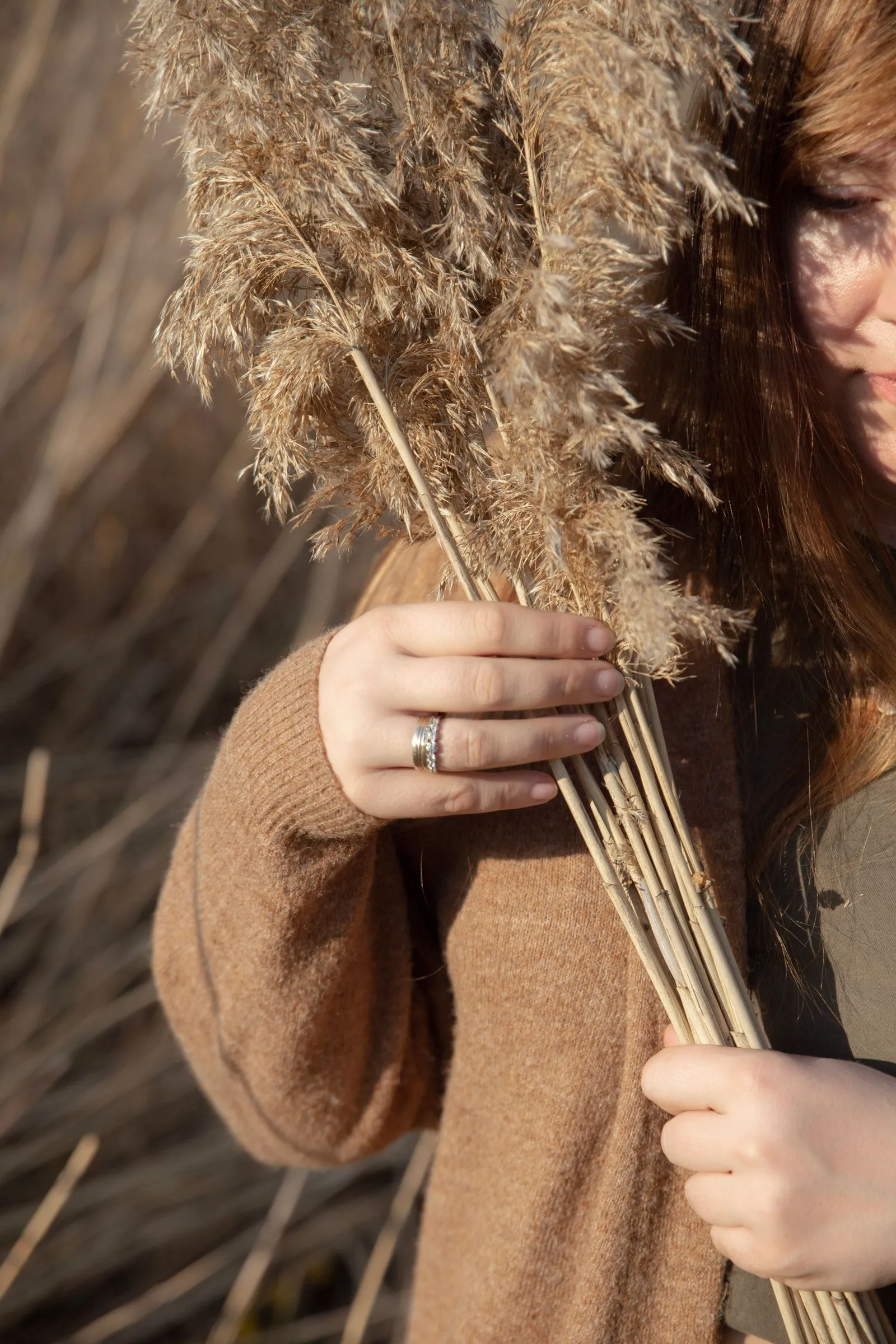 Hands holding dried grasses in warm, golden light
